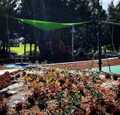 Green shade sail over a playground in a garden setting