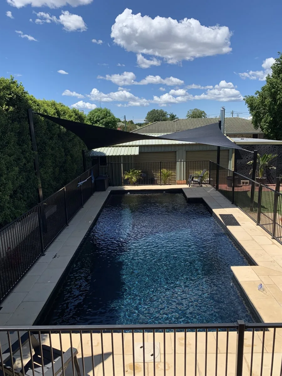 Charcoal waterproof shade sails over a residential backyard pool