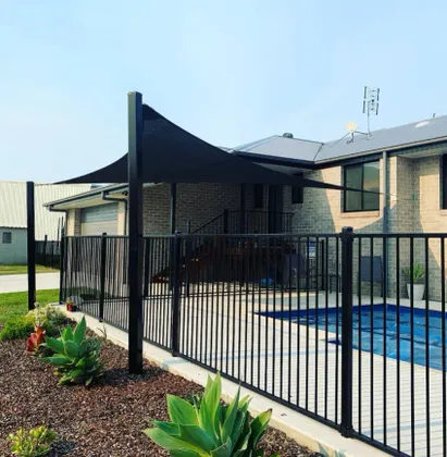 Charcoal residential shade sail installed over a backyard pool area